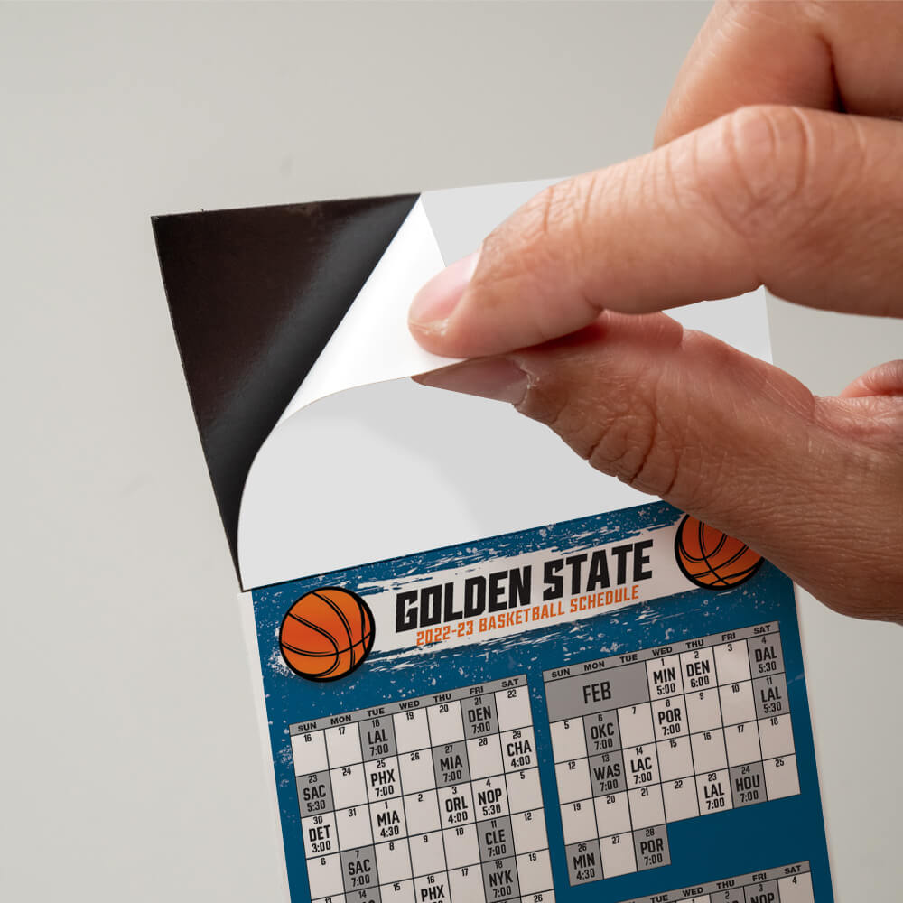 Peel and stick top on a Basketball schedule, peeling off the protective sheet to expose the adhesive
