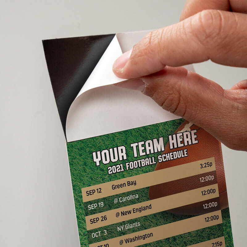 Peel and stick top on a football schedule, peeling off the protective sheet to expose the adhesive